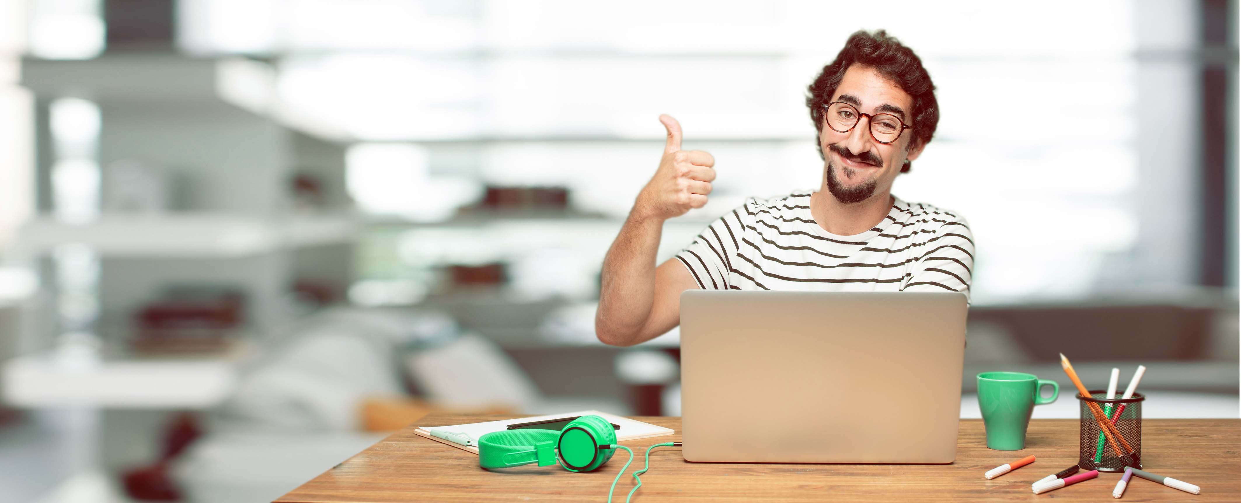 Hombre joven con un computador haciendo visto bueno con su pulgar arriba